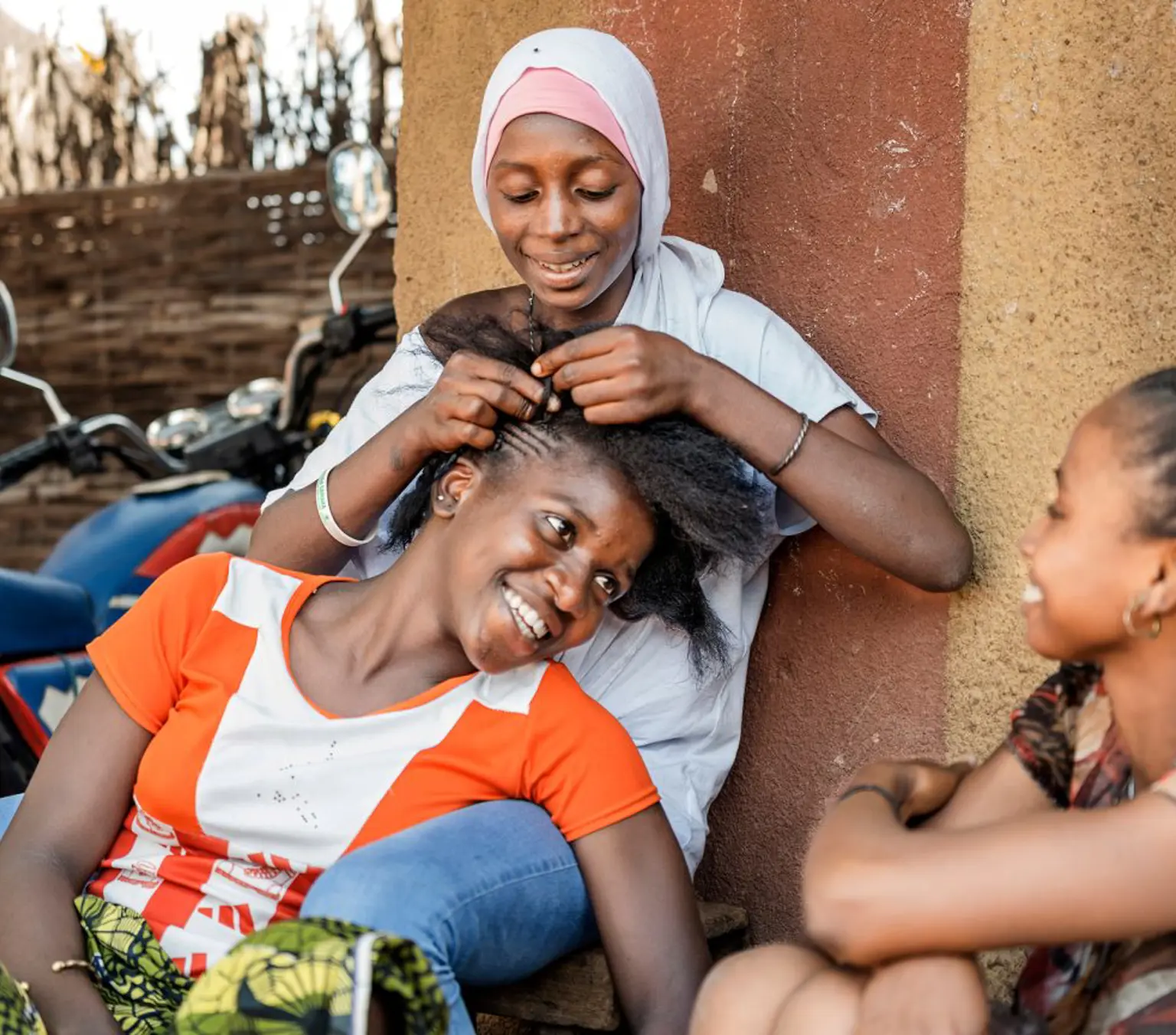 Afrikanske kvinder fletter hinandens hår