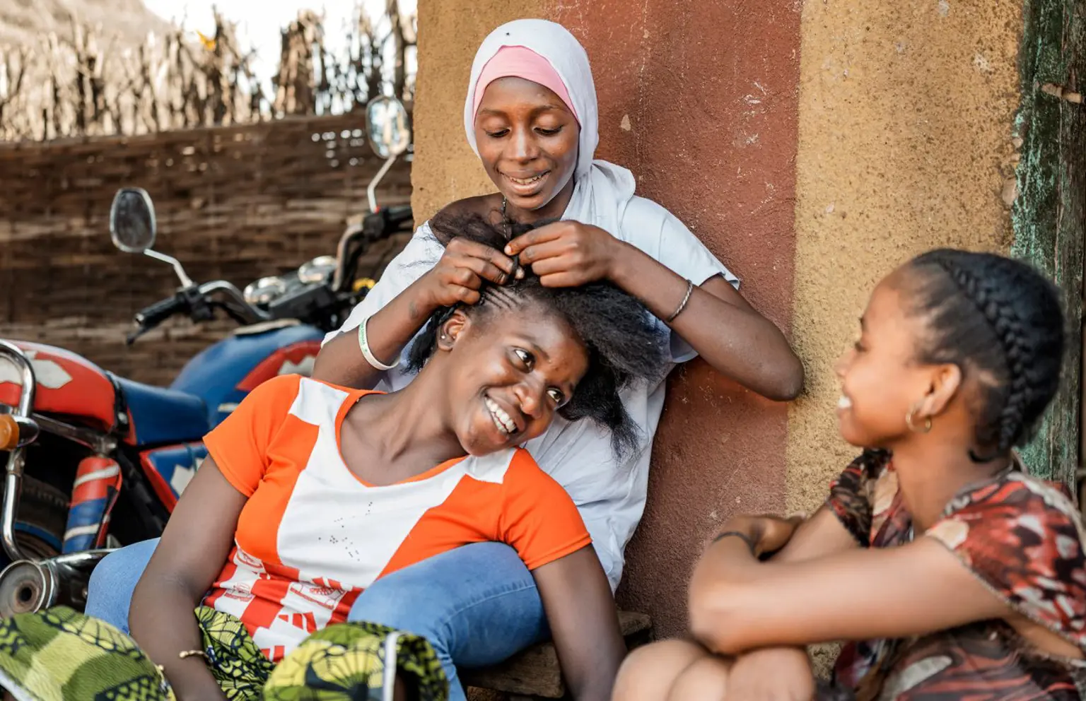 Afrikanske kvinder fletter hinandens hår