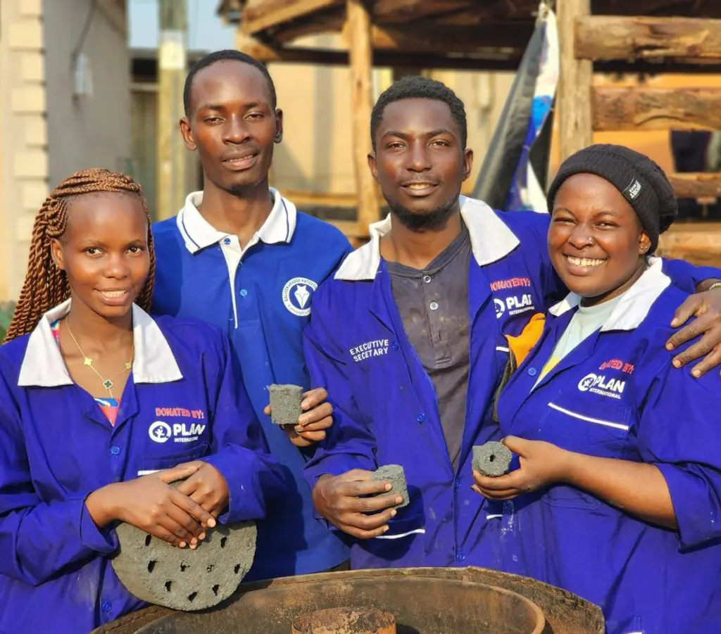 Unge fra Uganda viser deres arbejde frem til kameraet. De laver briketter af kul.