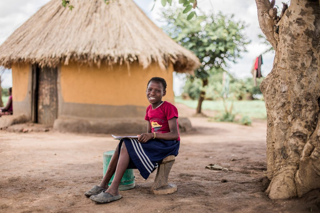 Pige i Zambia laver lektier under et træ