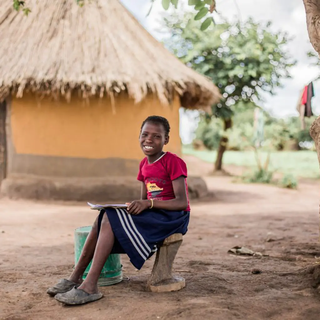 Pige i Zambia laver lektier under et træ