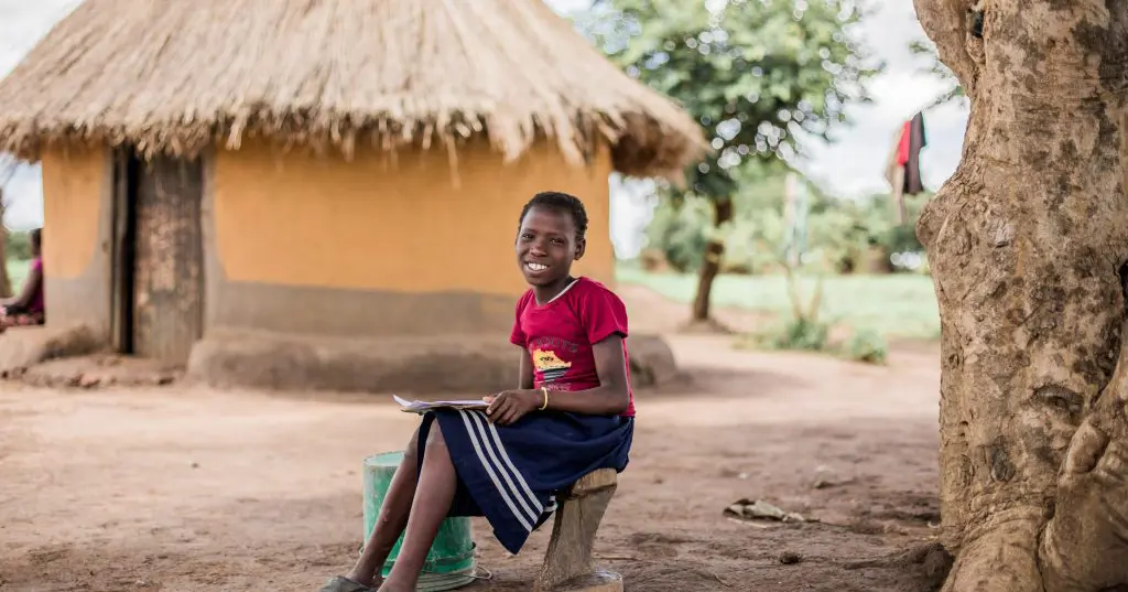 Pige i Zambia laver lektier under et træ