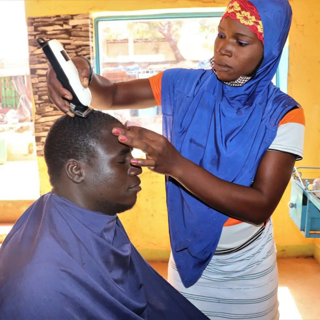 22-årige Clemence flygtede fra det nordlige Burkina Faso og har fået træning i iværksætteri. Som herrefrisør tjener hun nu mere og drømmer om egen salon. Danida-støtten gør det muligt for flere unge som hende at lære nye håndværk og starte egen forretning.