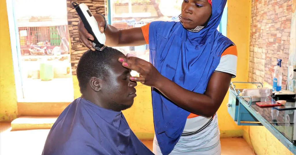 22-årige Clemence flygtede fra det nordlige Burkina Faso og har fået træning i iværksætteri. Som herrefrisør tjener hun nu mere og drømmer om egen salon. Danida-støtten gør det muligt for flere unge som hende at lære nye håndværk og starte egen forretning.